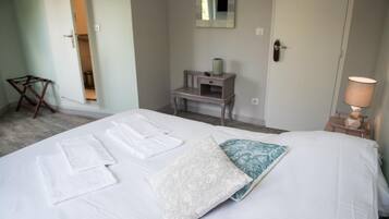 Ein Hotelzimmer mit einem Bett, einem Nachttisch mit Lampe, einem Spiegel an der Wand und einem kleinen Schreibtisch mit Stuhl.