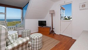 A cozy room with a checkered sofa set, a television, and a wooden cabinet. - Pikkewyntjie Cottage (Hermanus)