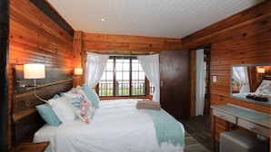Ein Schlafzimmer einer Holzhütte mit Bett, Nachttisch und einem Fenster mit Vorhängen.
