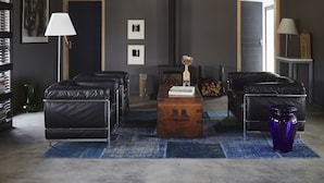 A modern living room with a high ceiling, exposed beams, a fireplace, leather sofas, a wooden coffee table, and a blue rug. - HaesFarm (Stanford)