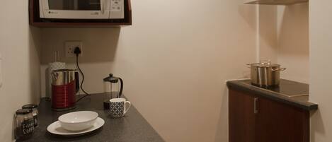 A kitchen with a microwave, coffee maker, and a pot on the counter.