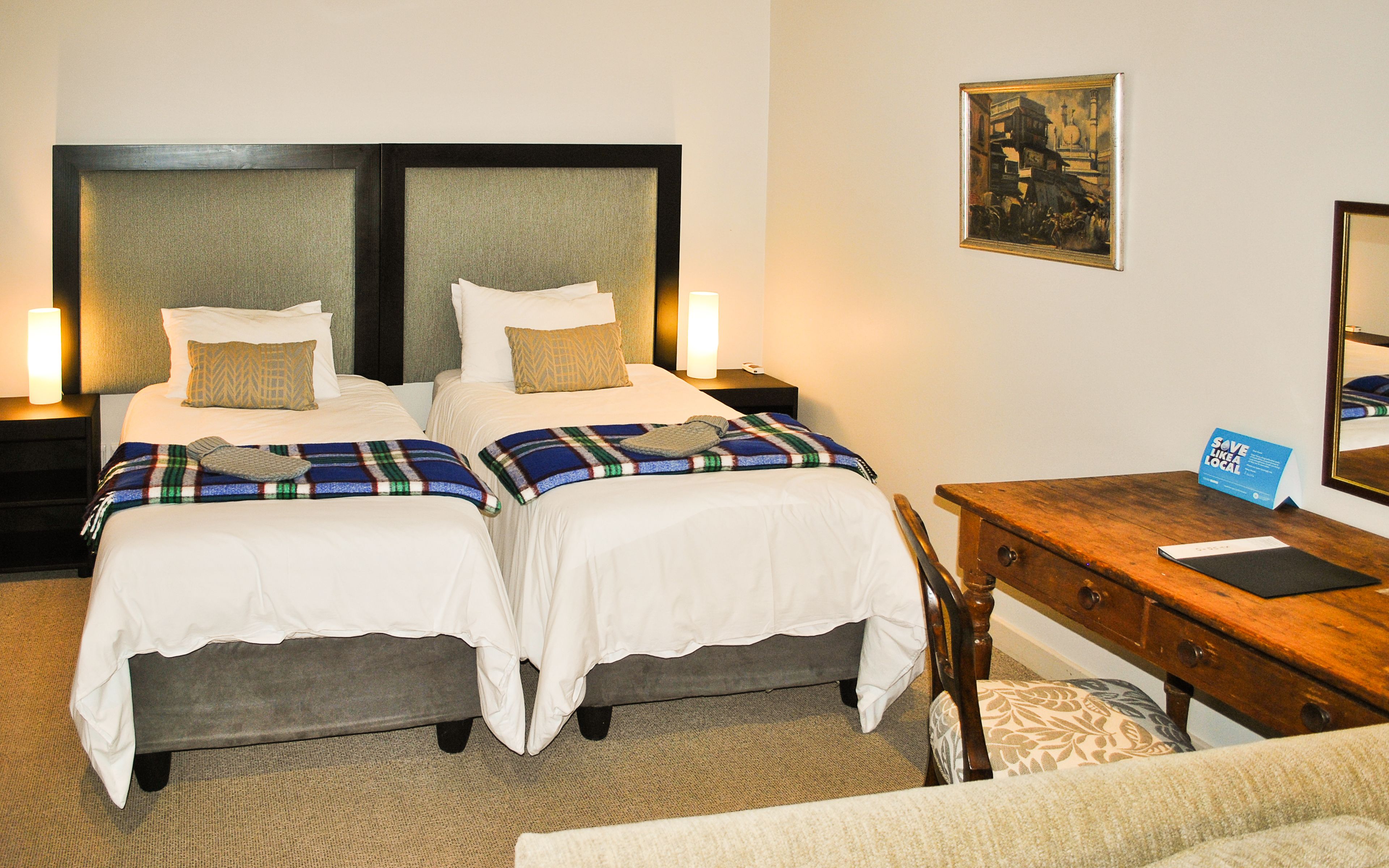 A hotel room with two beds, a desk, and a chair.
