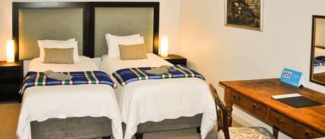 A hotel room with two beds, a desk, and a chair.