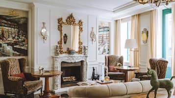 A classic interior with a fireplace, patterned chairs, and a green horse statue.