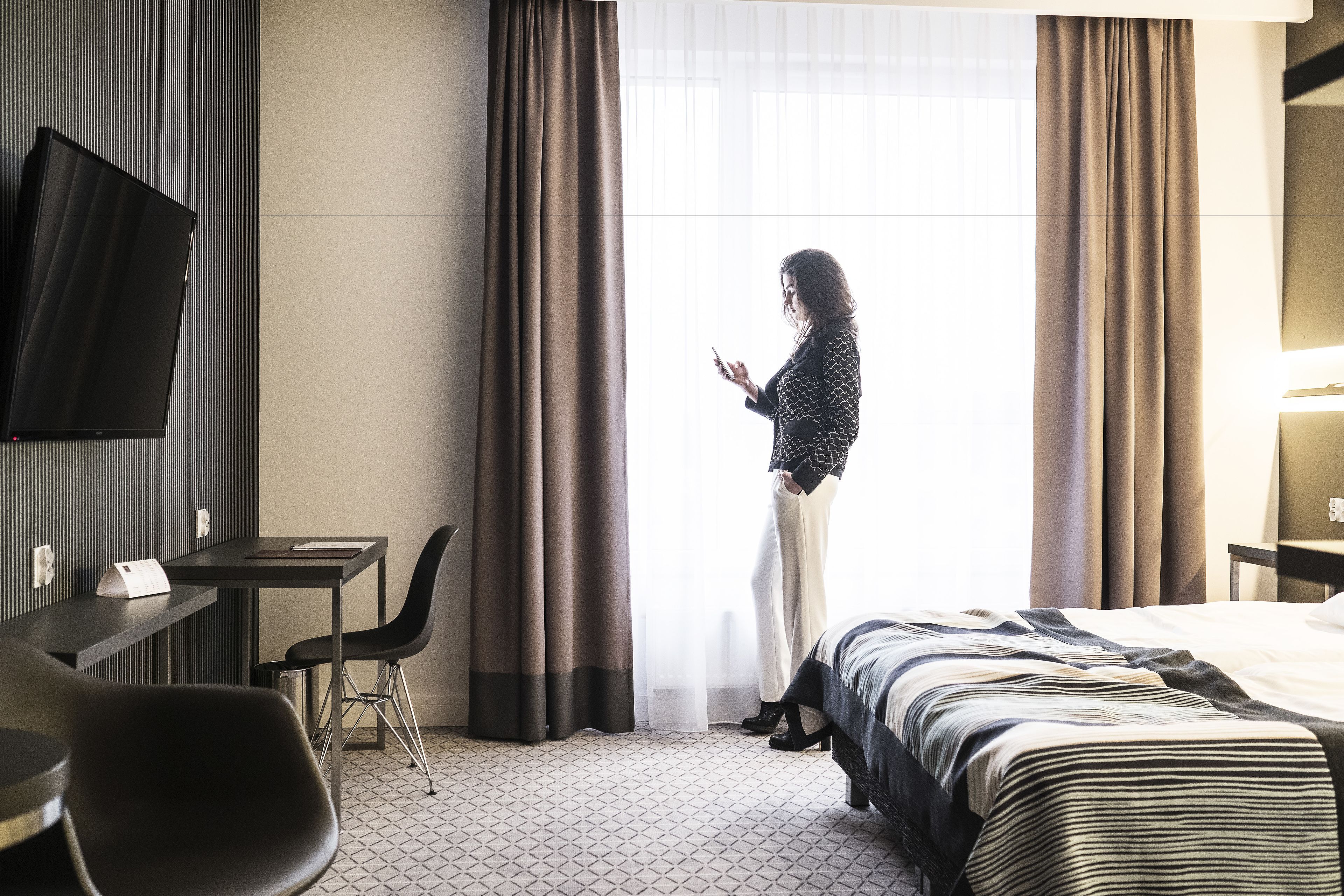 Una camera d'albergo con un letto, una scrivania, una sedia e una televisione.