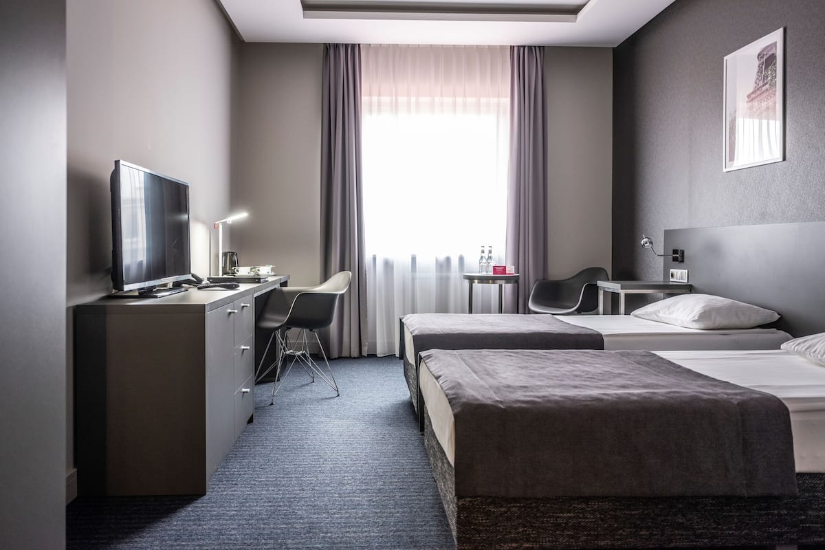 Een hotelkamer met een bed, een bureau met een computer, een stoel en een televisie.
