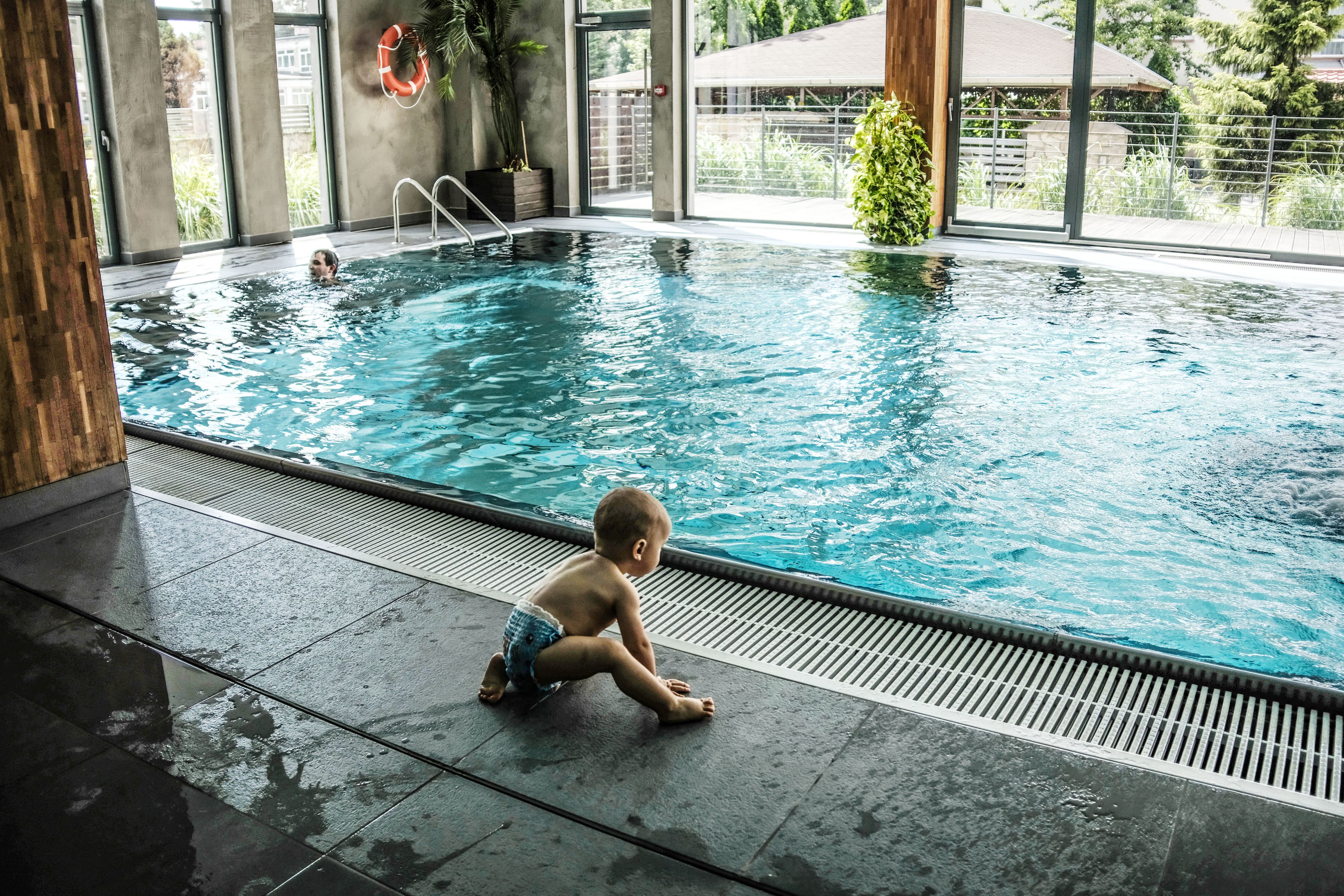 Piscina interna con un bambino seduto sul bordo.