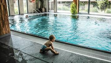 Piscina interna con un bambino seduto sul bordo.