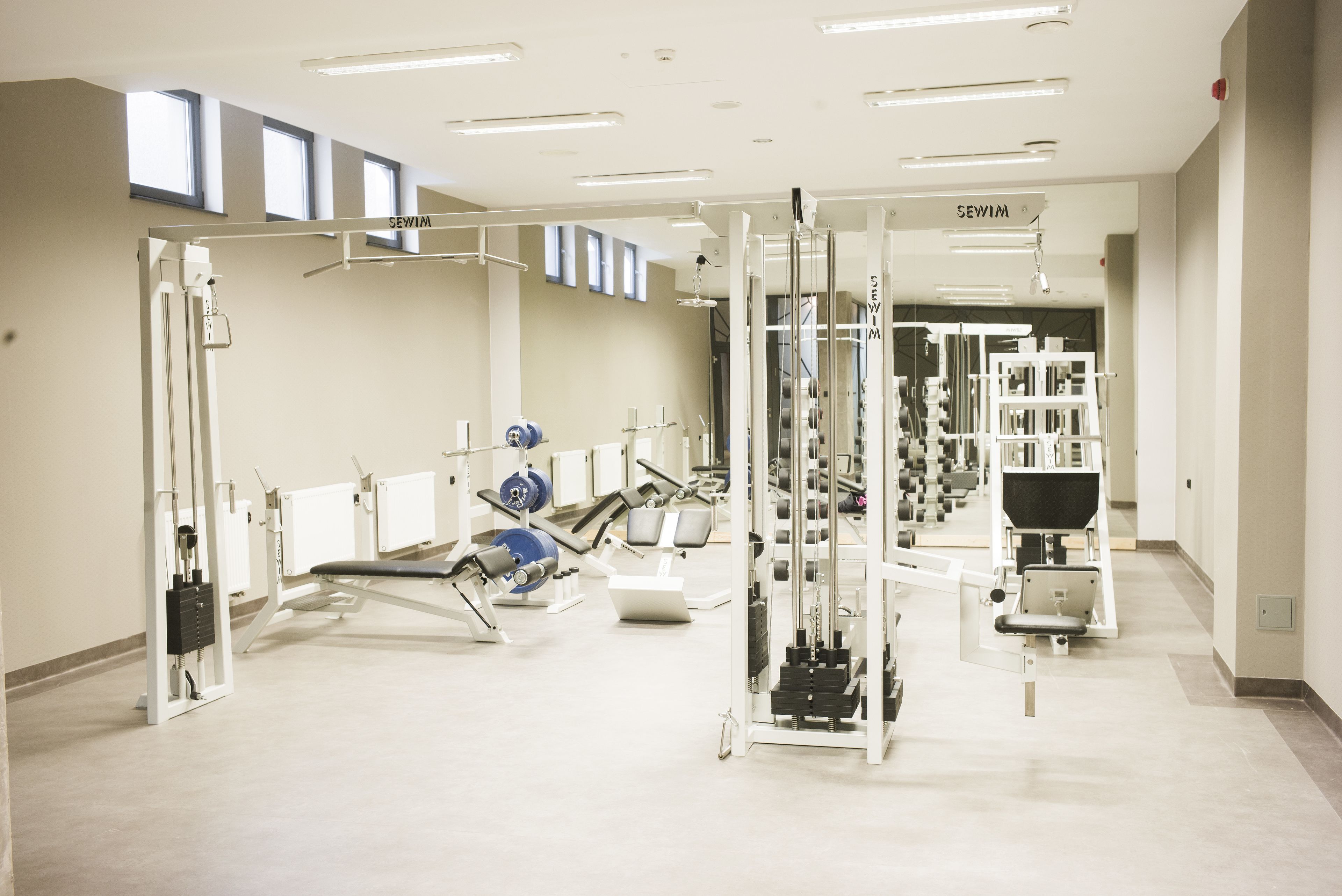 Een sportschool met diverse fitnessapparaten, waaronder krachttoestellen en een squatraam.