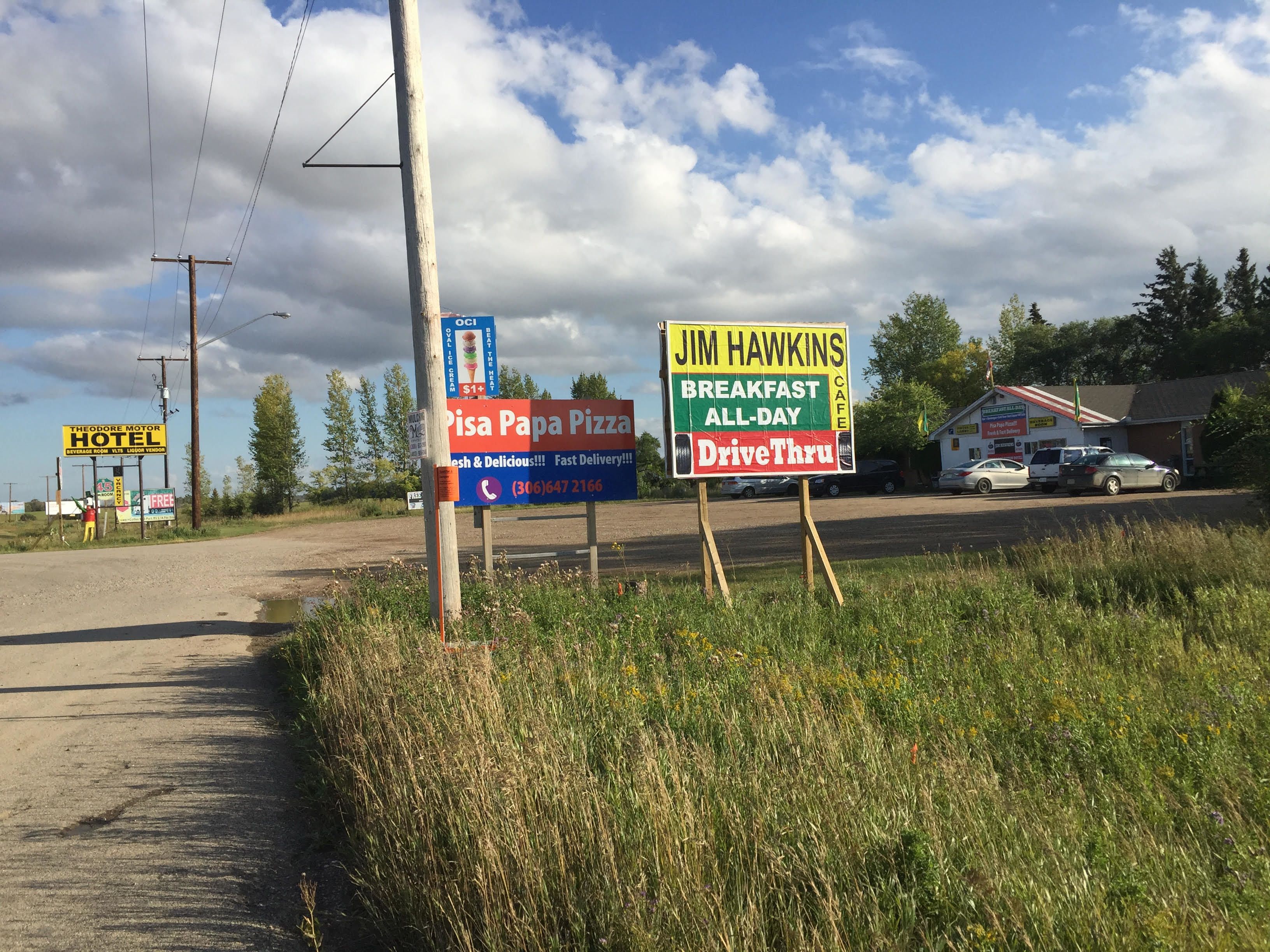 A roadside sign for Jim Hawkins Breakfast All-Day Cafe, offering breakfast and drive-thru service.