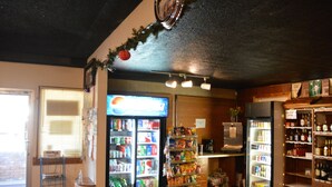 A small convenience store with refrigerated sections, shelves stocked with snacks, and a coffee machine. - Theodore Motor Hotel (Theodore)