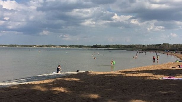 A beach with people swimming and walking along the shore. - Theodore Motor Hotel (Theodore)