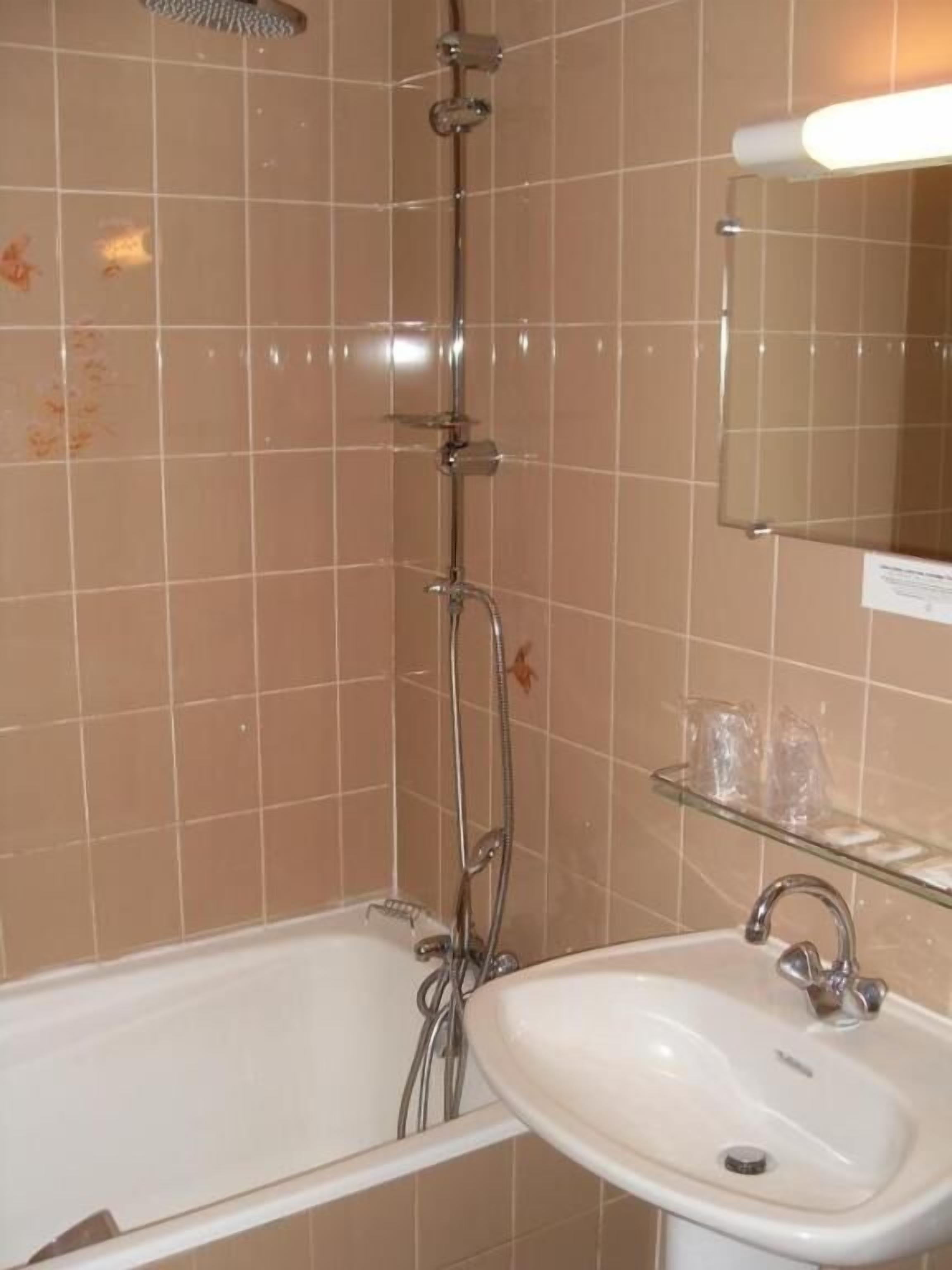 A bathroom with a bathtub, a sink, and a glass shelf with toiletries.