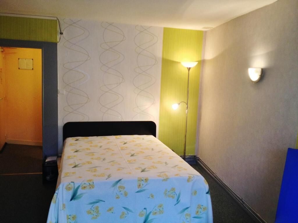 Una habitación de hotel con una cama, una lámpara de pared y una puerta.