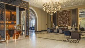 Um hall amplo com um candelabro, área de estar e troféus decorativos.