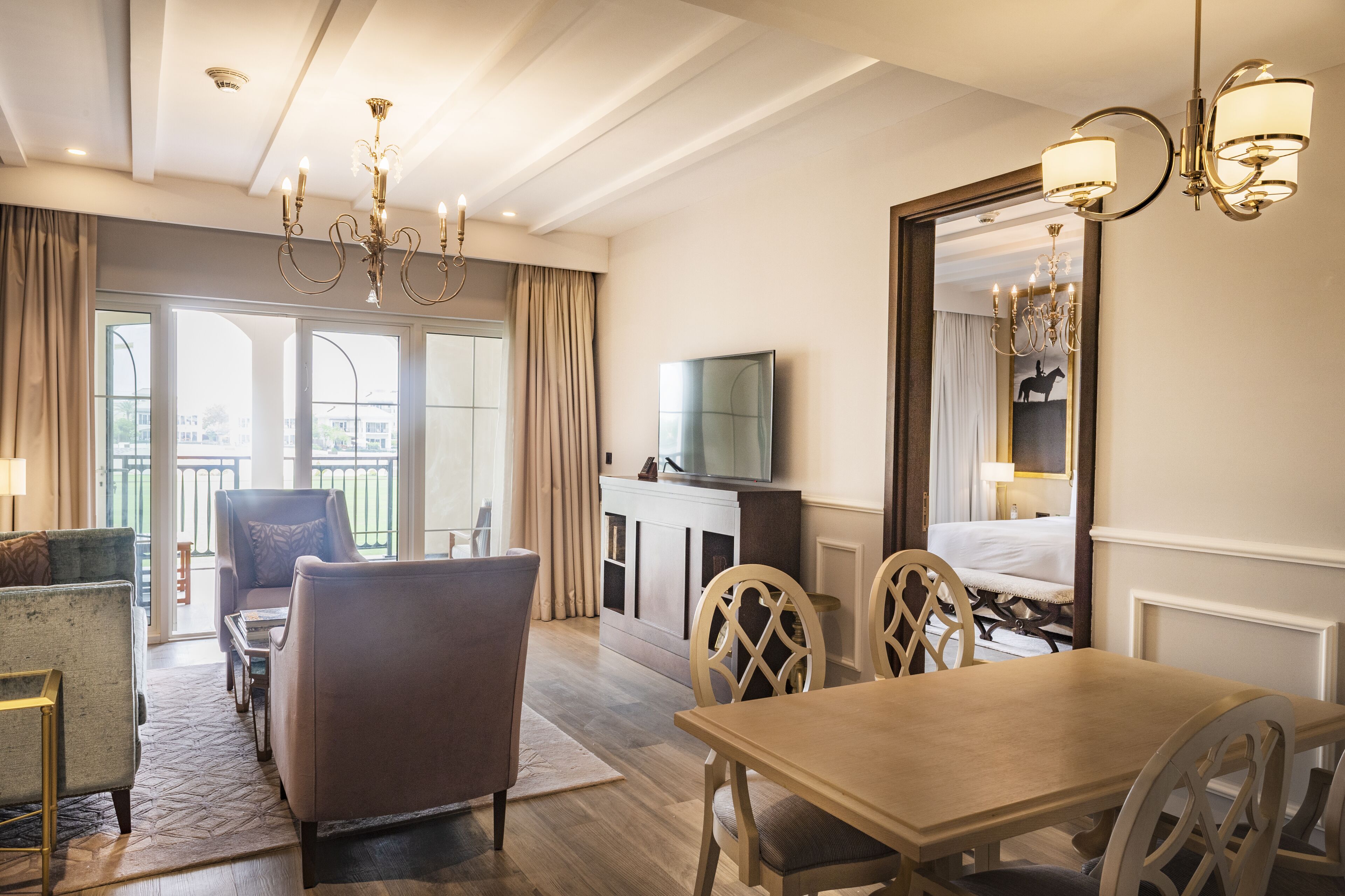 A hotel room with a dining area, a TV, and a large mirror.