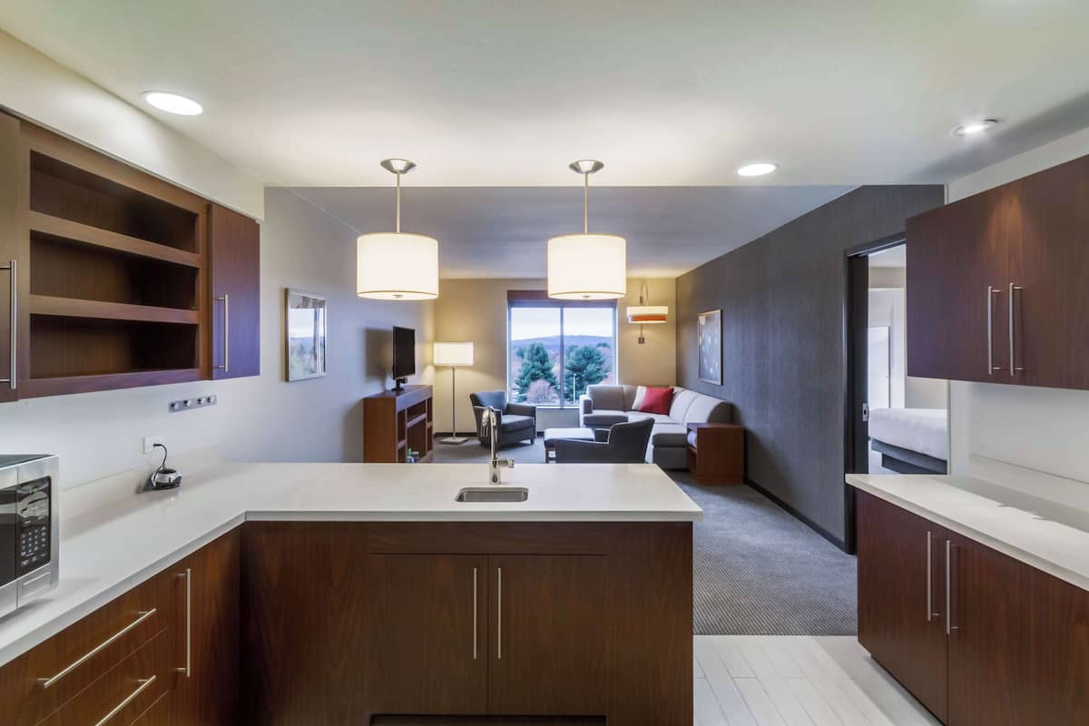 A modern kitchen with a central island, wooden cabinets, and pendant lighting.