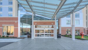 Una entrada moderna a un edificio con puerta de cristal, una marquesina y fachada de ladrillo.