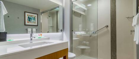 A modern bathroom with a glass-enclosed shower, a white sink, and a wooden vanity.