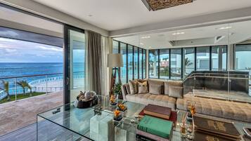 A modern living room with a glass coffee table, a sofa, and a view of the ocean.