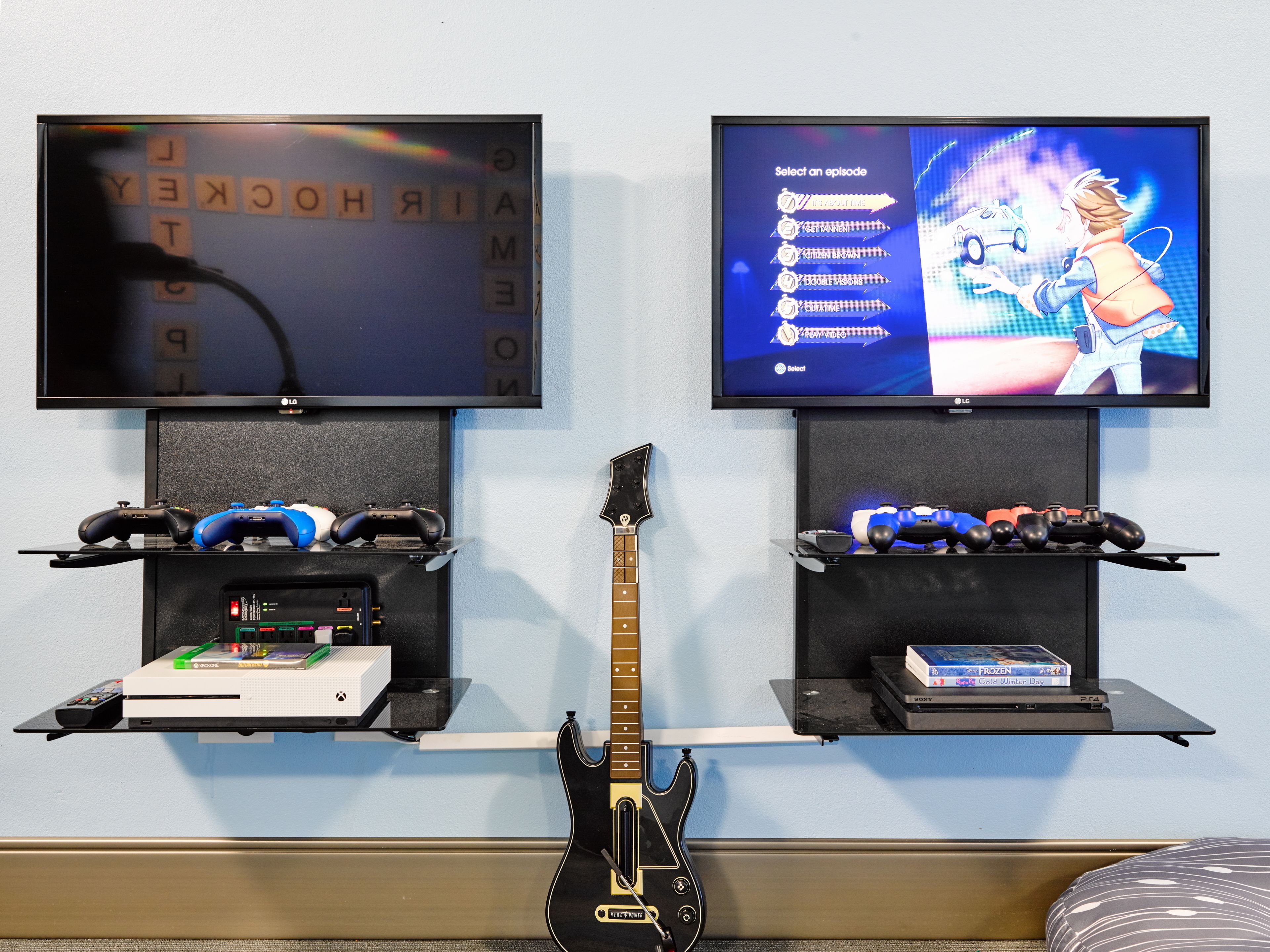 Due televisori a parete, ciascuno con una console di gioco e una chitarra.