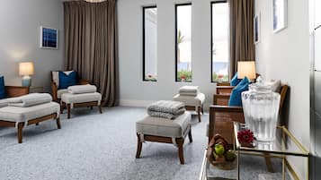 A modern hotel room with a large window, a chandelier, and a view of the sea.