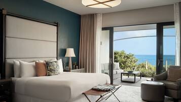 Habitación de hotel moderna con una cama grande, un escritorio, una silla y vistas al océano.