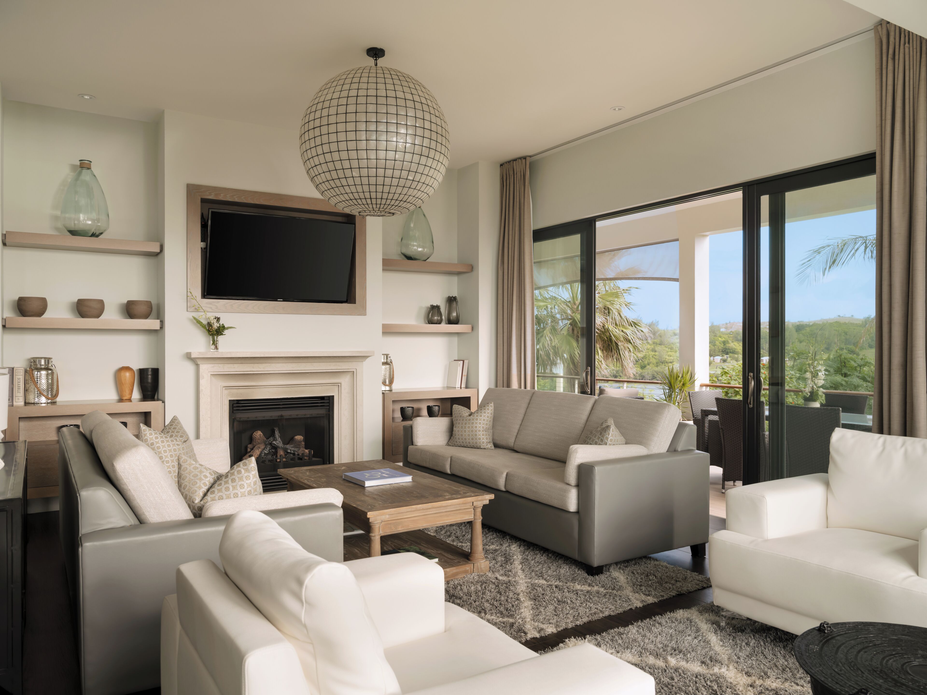 Una sala de estar moderna con chimenea, sofás, una mesa de centro y un televisor grande.