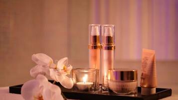 A tray with skincare products, a candle, and white flowers.