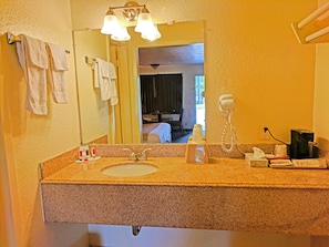 A bathroom with a granite countertop sink, a mirror, a hairdryer, and towels hanging on a rack. - Motel 6 Houston, TX – Hobby Airport (Houston)