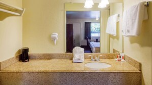 Ein Badezimmer im Hotel mit einer Granitablage, einem Waschbecken, einem Spiegel, einem Fön und Handtüchern.
