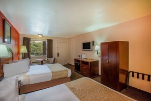 A hotel room with two beds, a desk, a TV, and a wardrobe. - Travelodge by Wyndham Houston Hobby Airport (Houston)