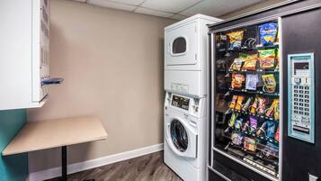 A laundry room with a washing machine and a vending machine.