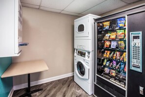 A laundry room with a washing machine and a vending machine. - Motel 6 Houston, TX – Hobby Airport (Houston)