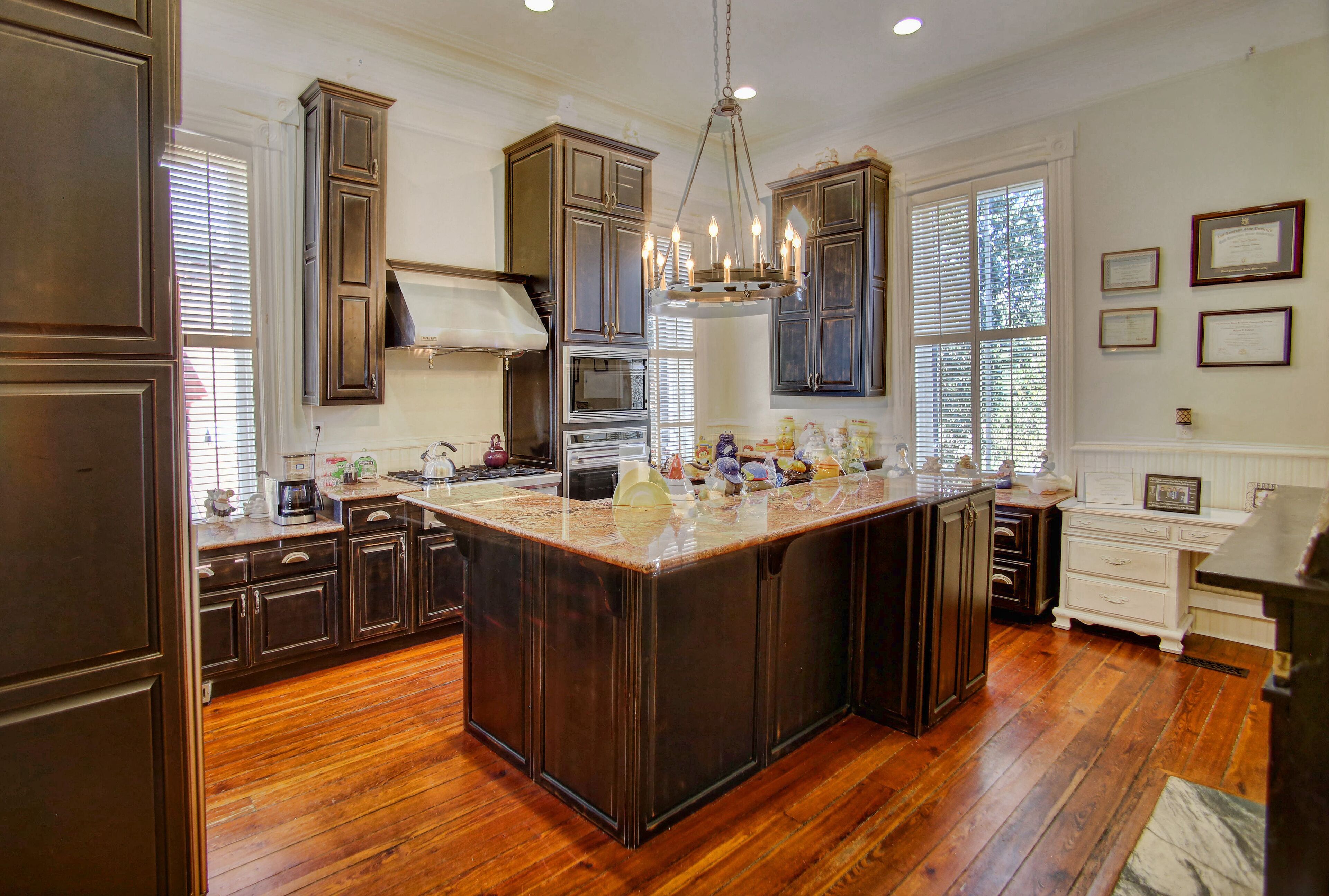 A spacious kitchen with dark wooden cabinets, a large island, and a chandelier.