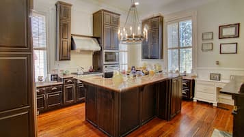 A spacious kitchen with dark wooden cabinets, a large island, and a chandelier.