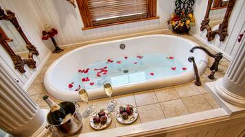 A luxurious bathroom with a bathtub filled with rose petals, champagne, and strawberries.