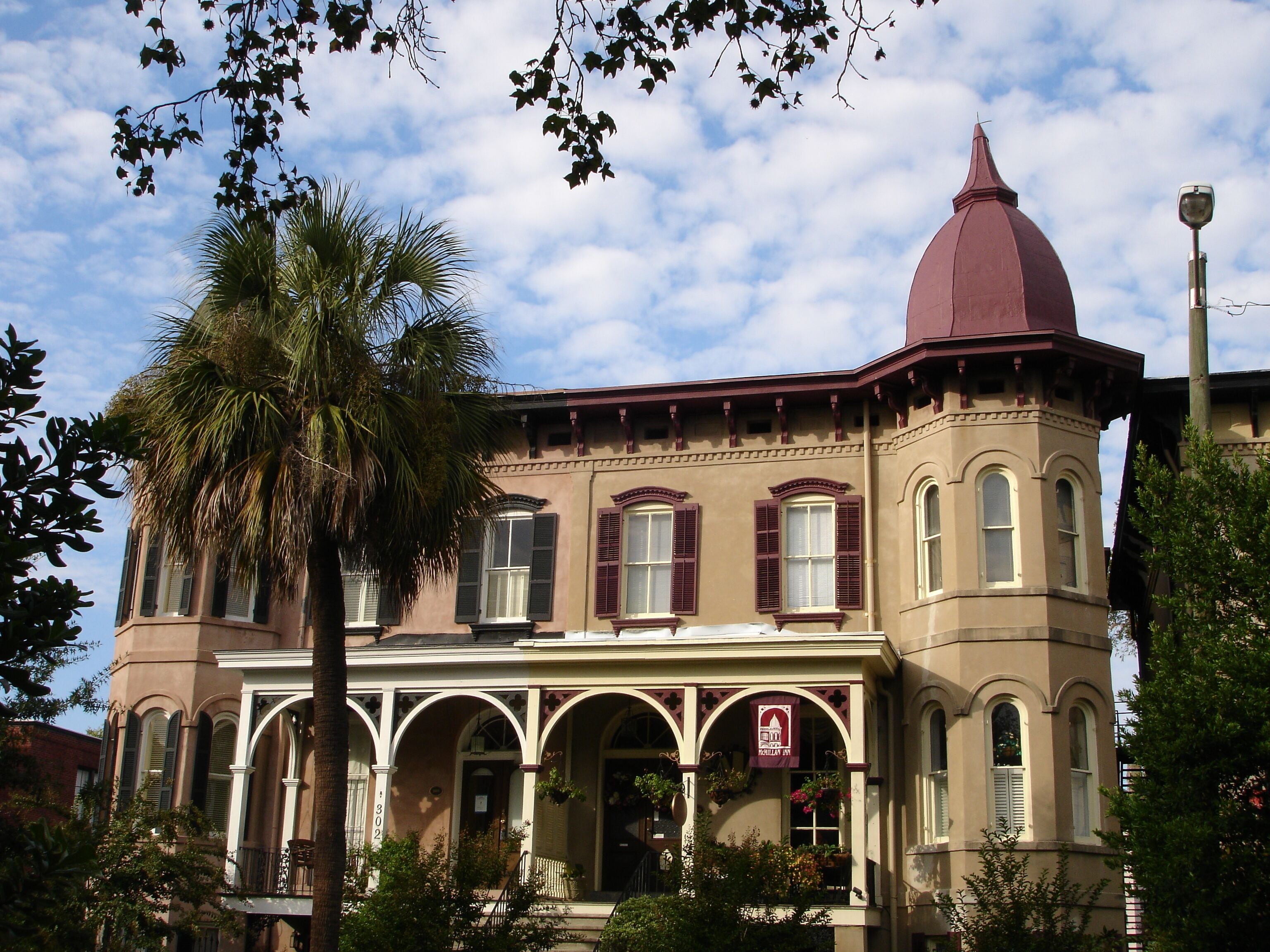 A historic building with a central dome, arched windows, and a covered porch.