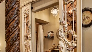 Un couloir somptueux, orné d’une colonne en bois, d’un miroir décoré de motifs floraux et d’un lustre.