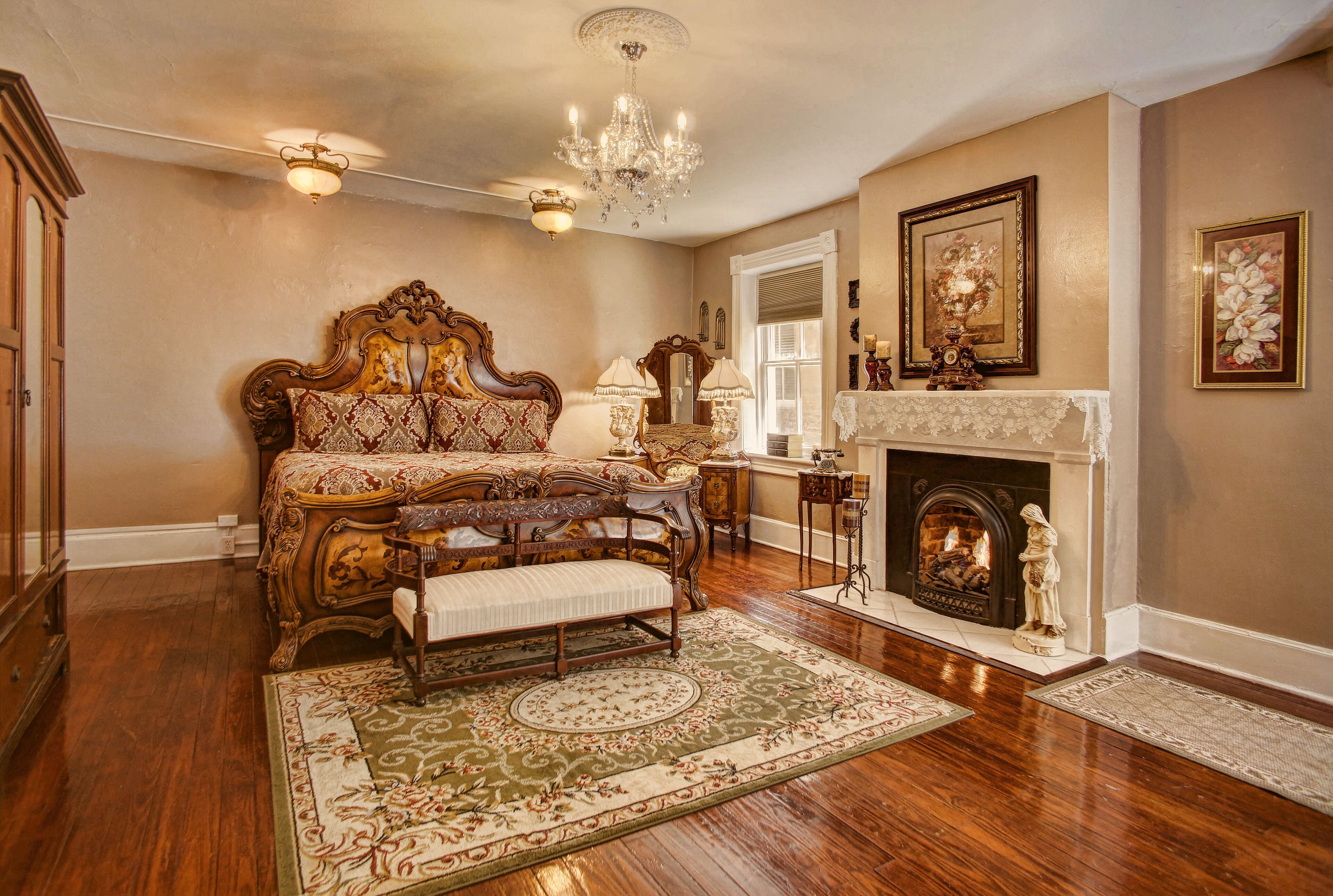 A spacious bedroom with a large bed, a fireplace, and a chandelier.