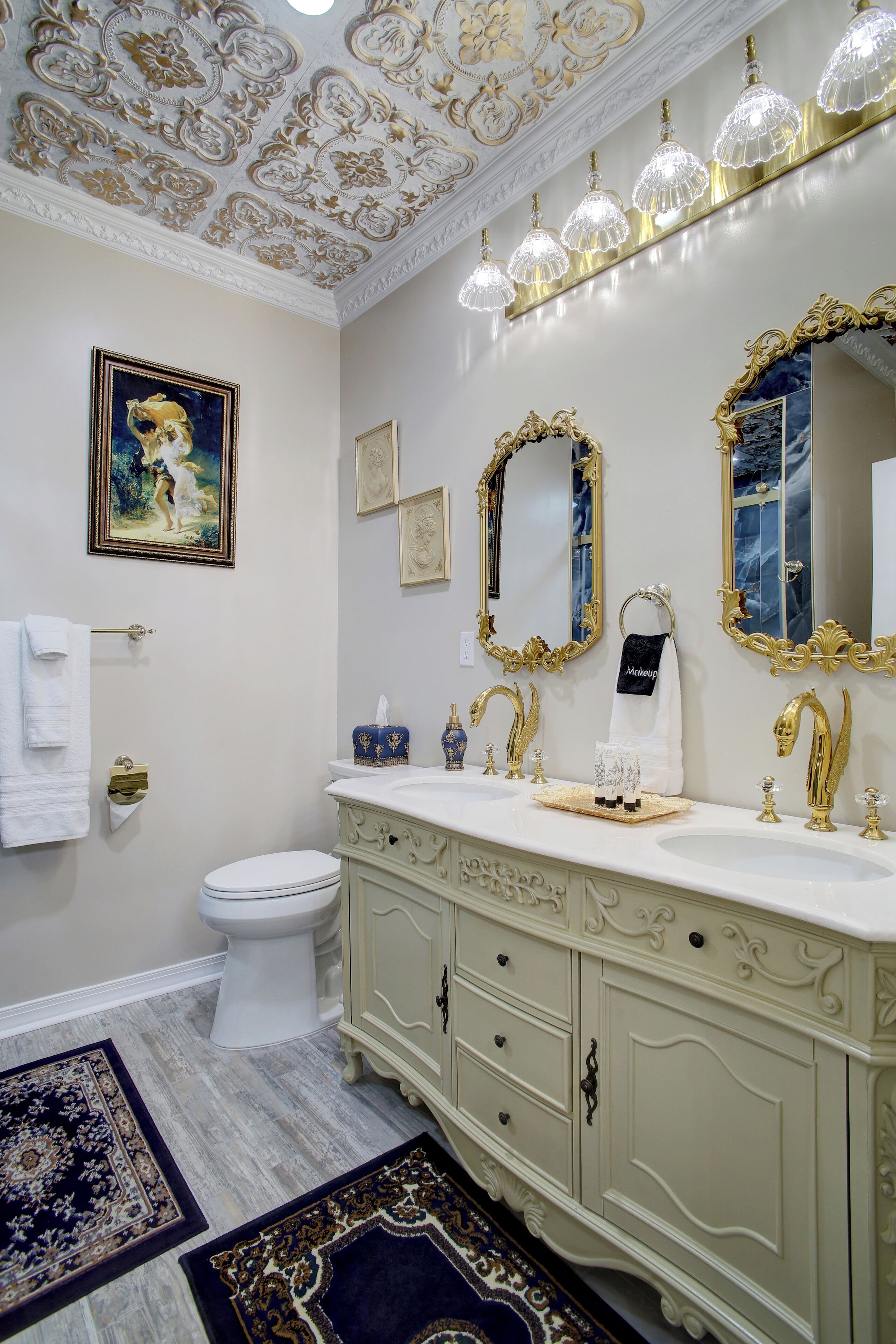 A luxurious bathroom with ornate gold mirrors, a marble sink, and a classic toilet.