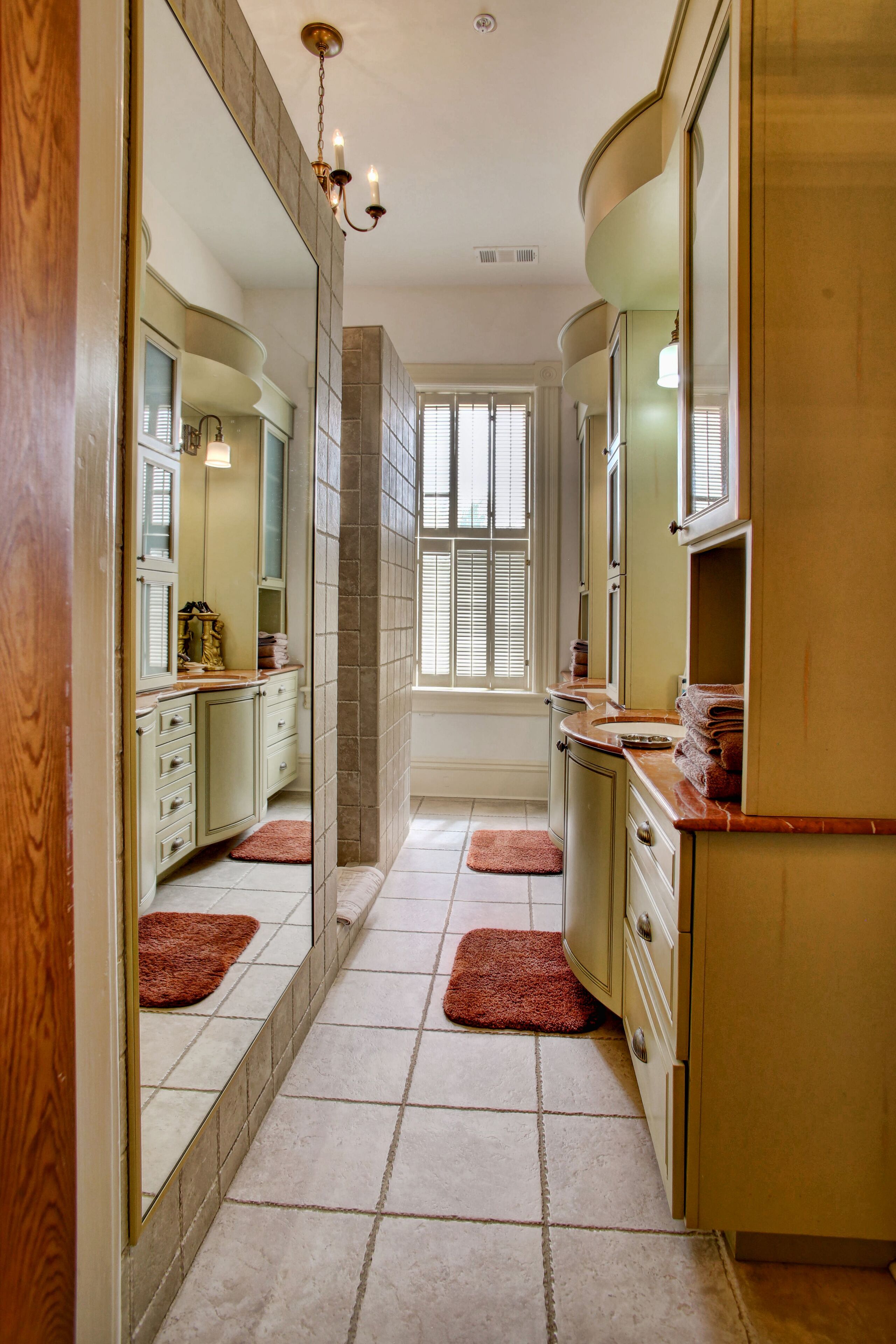 A narrow bathroom with a vanity, a mirror, and a window.