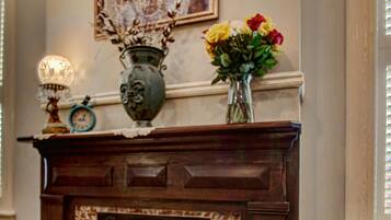 A fireplace with a brick surround, a vase with flowers, and a framed artwork above it.