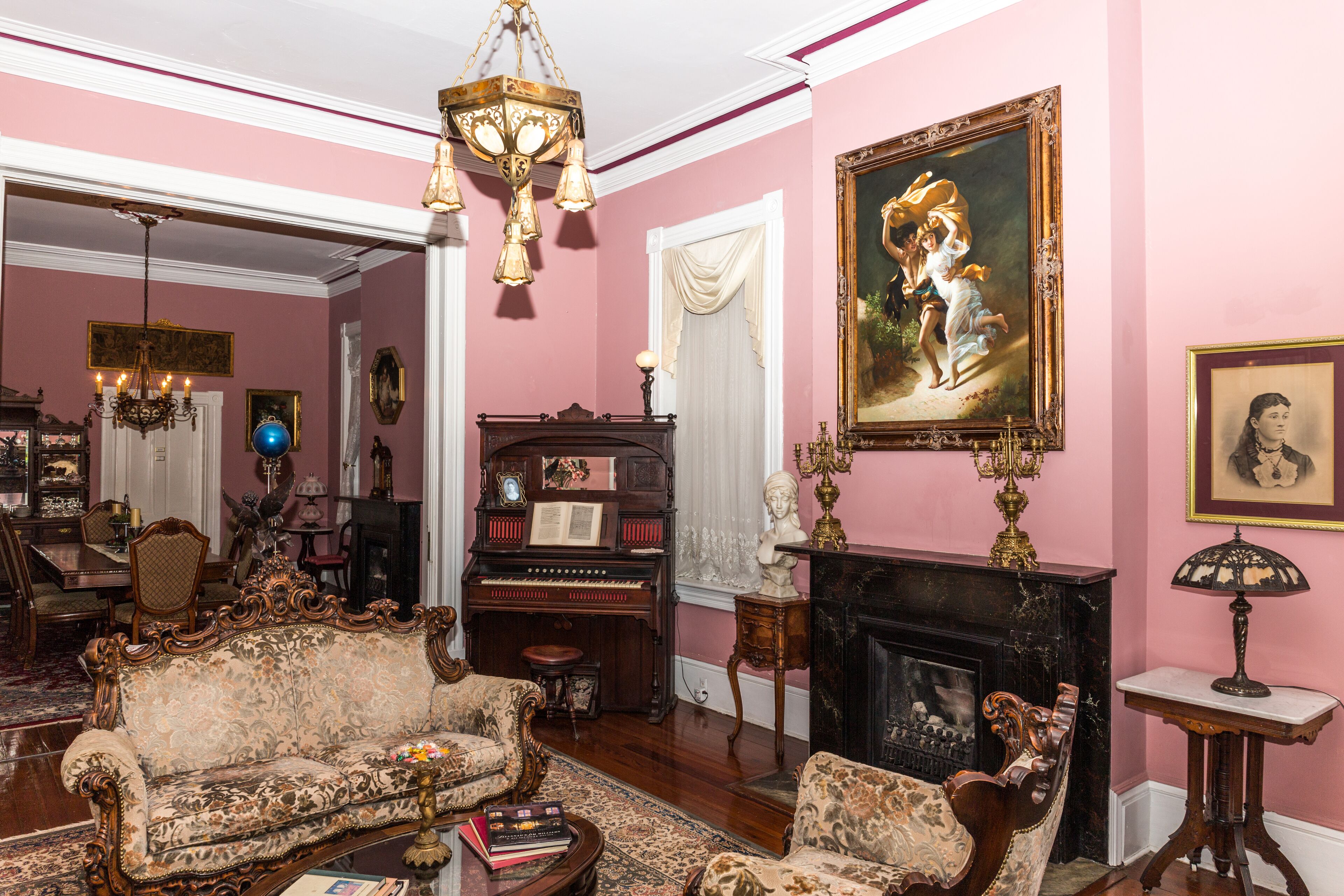 A room with a piano, a sofa, a fireplace, and a chandelier.