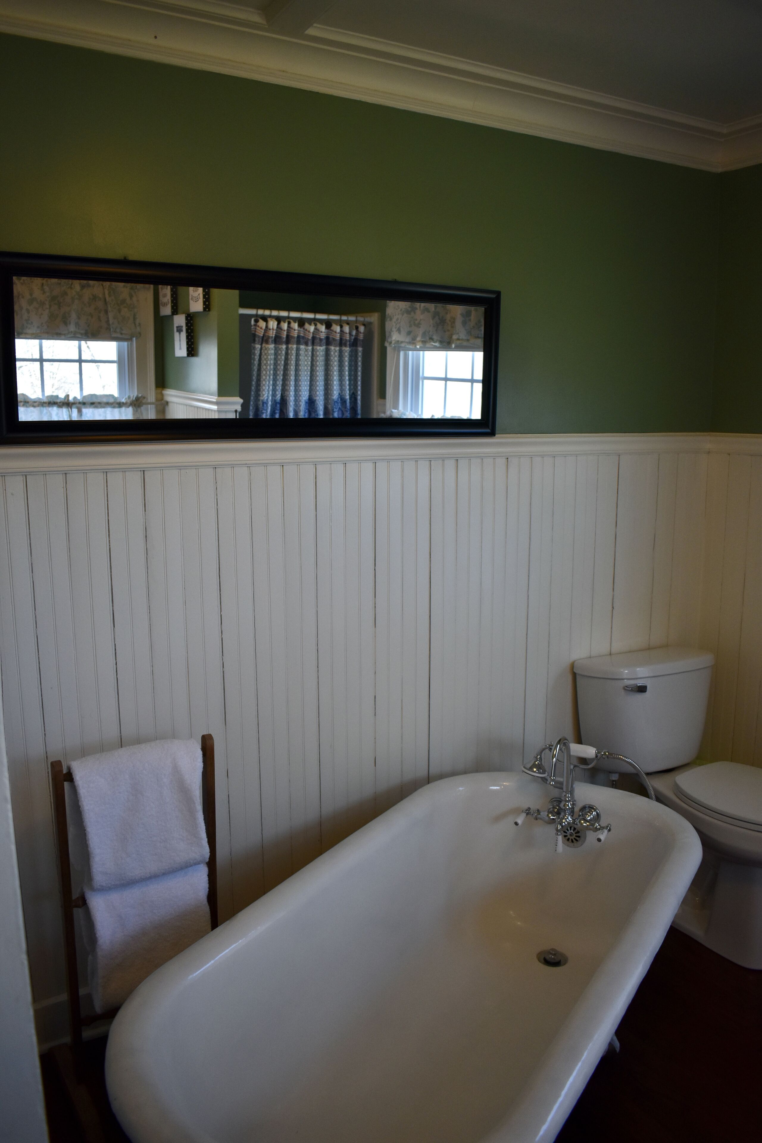 Ein Badezimmer mit einer weißen Badewanne, einer Toilette und einem Spiegel über dem Waschbecken.