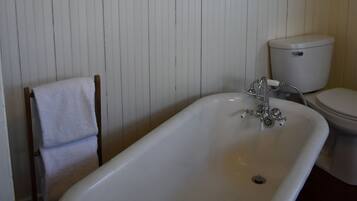 Ein Badezimmer mit einer weißen Badewanne, einer Toilette und einem Spiegel über dem Waschbecken.