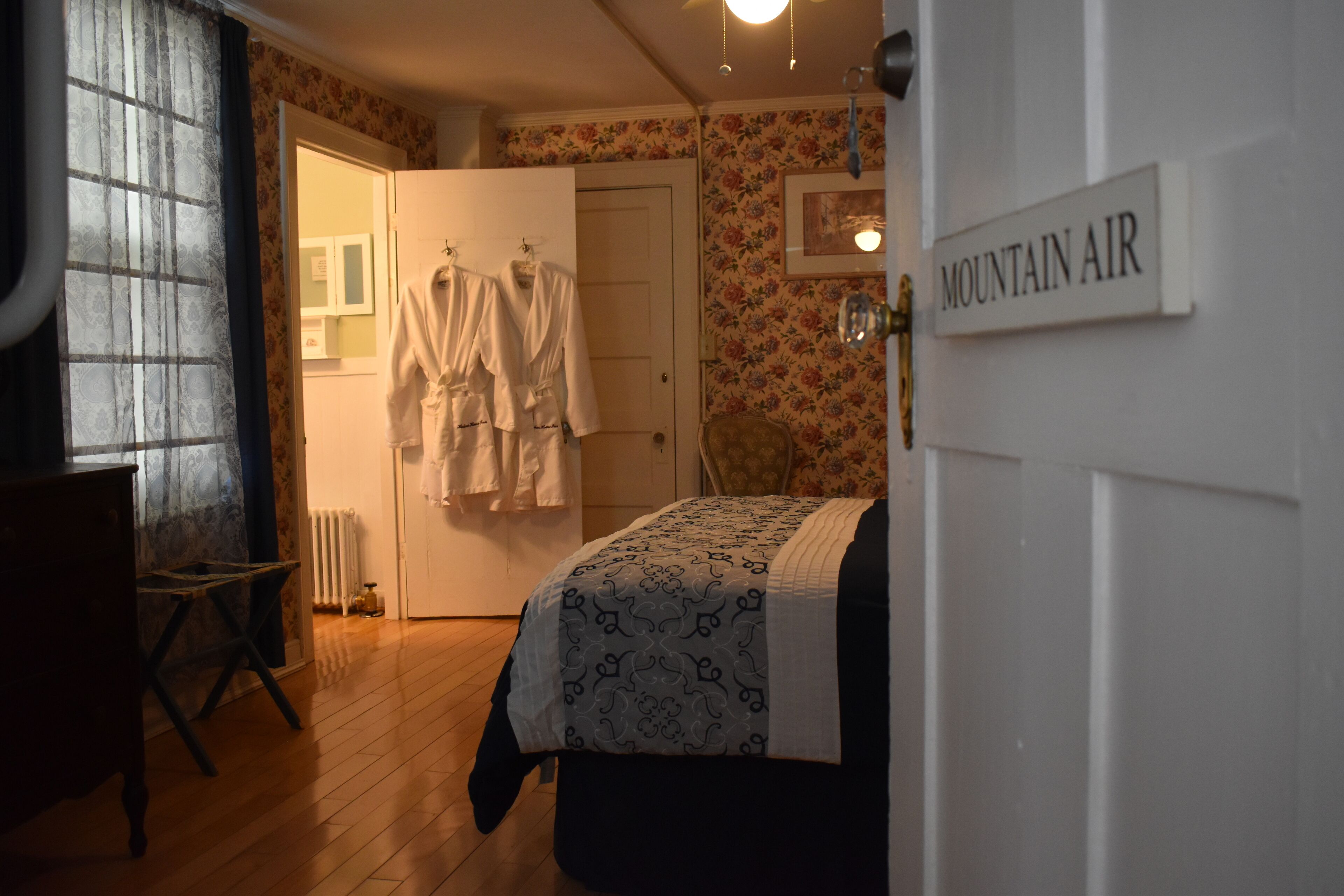 Camera da letto con un letto, una sedia, un termosifone e una porta con la scritta "MOUNTAIN AIR".