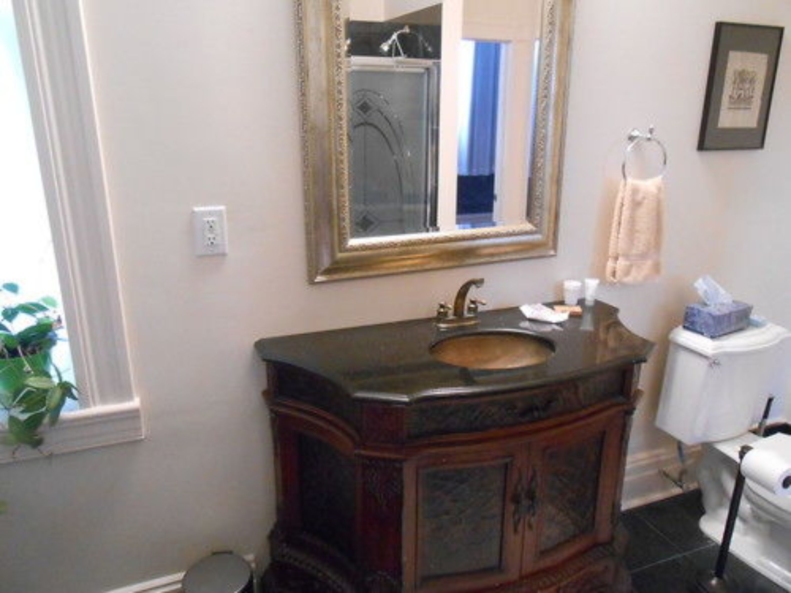 A bathroom with a wooden vanity, a sink, a mirror, and a toilet.