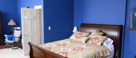 A bedroom with a wooden bed, blue walls, and a white door.