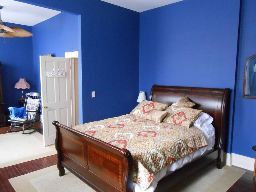 Ein Schlafzimmer mit einem hölzernen Bett, blauen Wänden und einer weißen Tür.